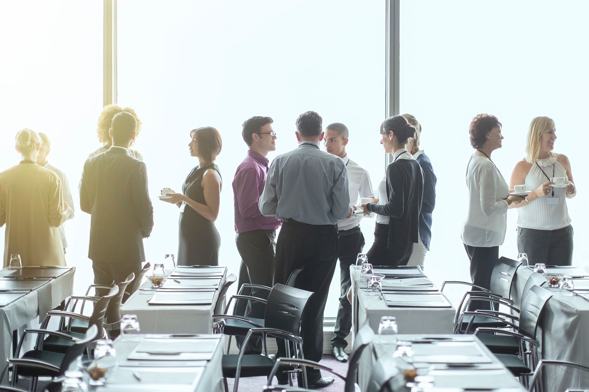 Geschäftsleute bei einem Networking-Event im Konferenzraum Menschen stehen in einer Gruppe mit Kaffeetassen in einem Konferenzraum und unterhalten sich.