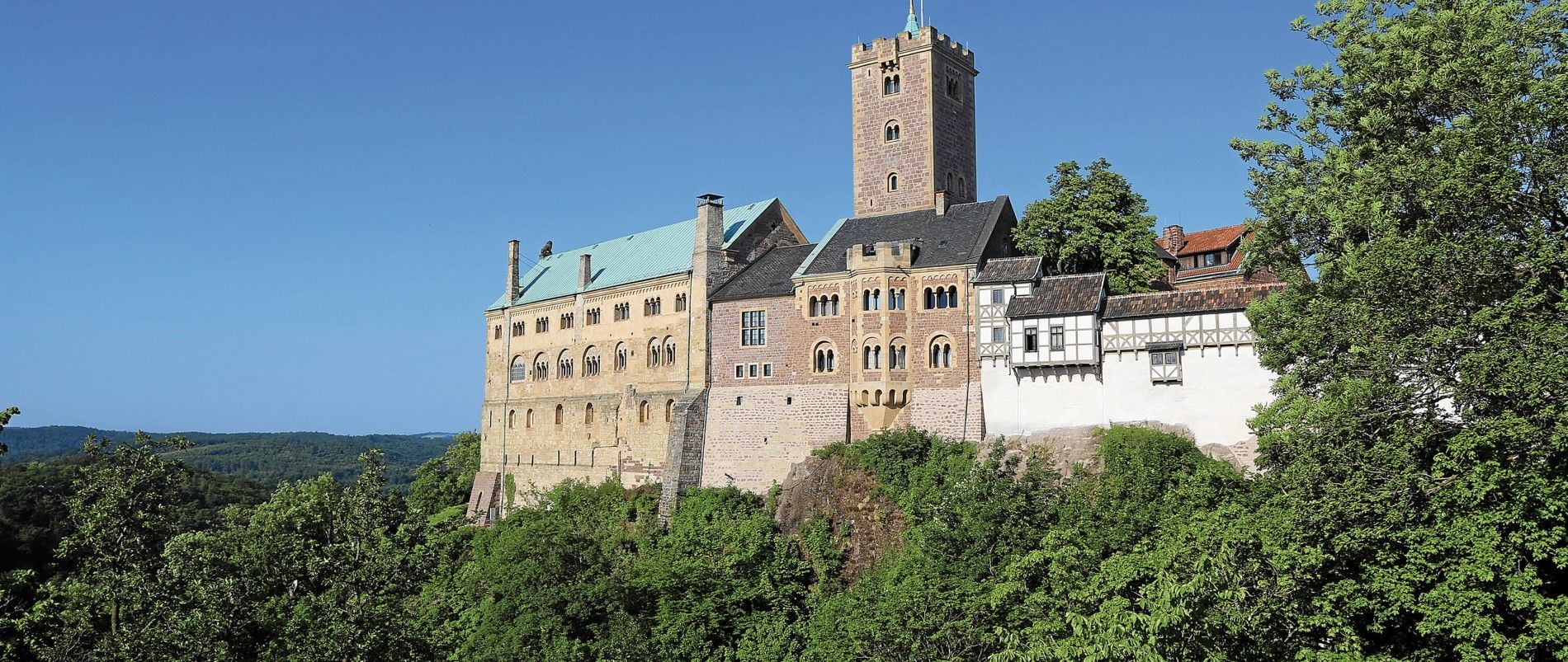 Schloss auf einem Hügel umgeben von Bäumen bei klarem Himmel