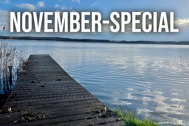 Ein ruhiger See mit Holzsteg unter weitem Himmel lädt zum entspannten November-Special ein.
