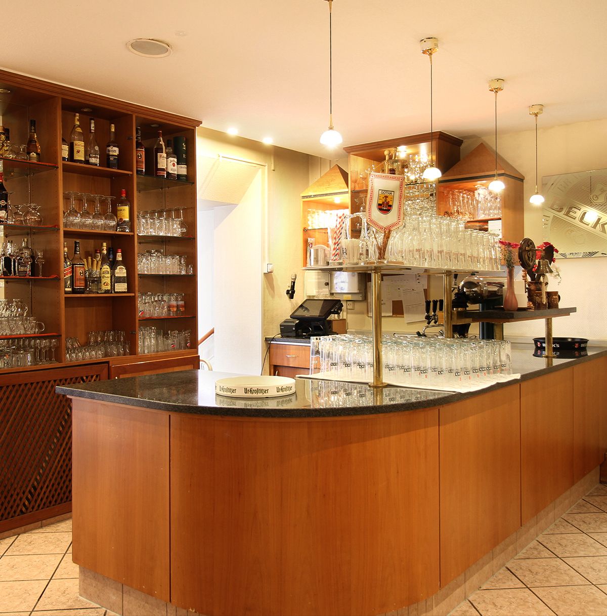 Eine elegante Bar mit Holztheke, Gläsern und Spirituosenregal.