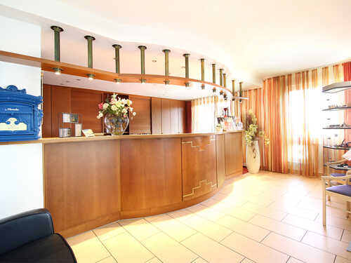 Eine Frau in roter Jacke steht am Empfang eines Hotels, dekoriert mit Weihnachtsbaum.